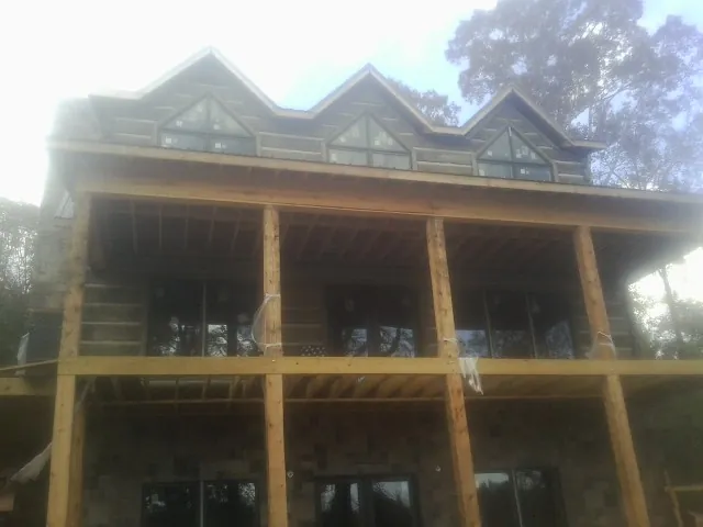 Dormers and porch framing on a large log home under construction — Roof Coating work by our crew in Berkley