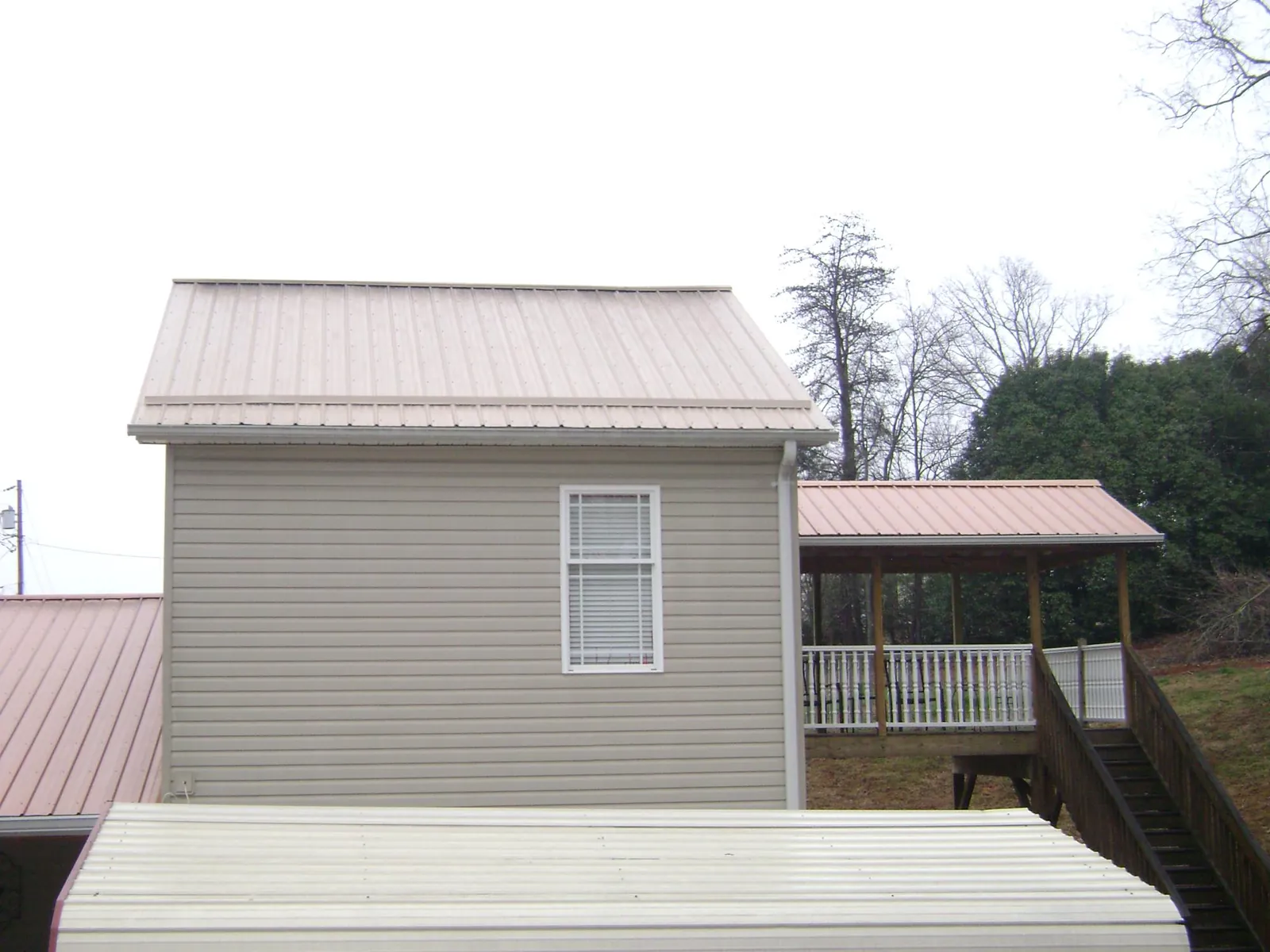 Tan metal roofs on a two story addition and attached porch, from a Roof Replacement job in Berkley